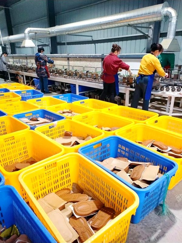 Factory workers assembling sole components in production facility